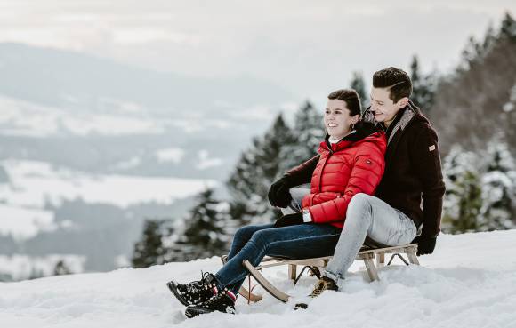 Paar beim Schlittenfahren im Allgäu