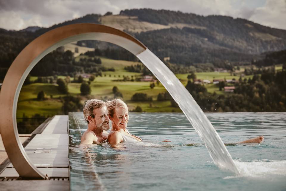 Paar beim Baden im Infinitypool mit Blick auf die Nagelfluhkette im Allgäu