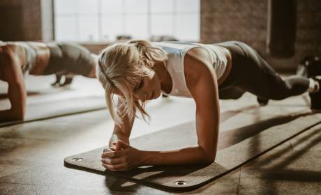 Frau macht Plank auf Gymnastikmatte