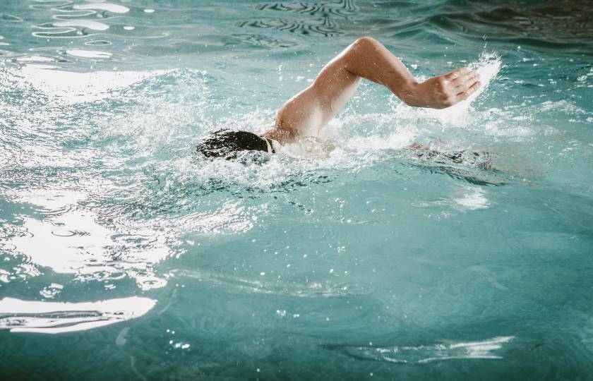 Mann schwimmt Bahnen in Innenpool